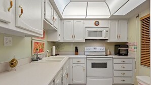 Eine Küche mit weißen Schränken, einer Mikrowelle, einem Backofen und einem Spülbecken.