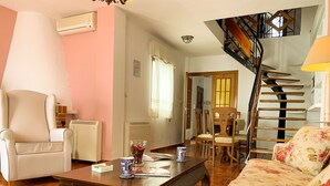 Un salon comprenant un canapé, un fauteuil, une table basse en bois et un coin repas avec des chaises et une table.