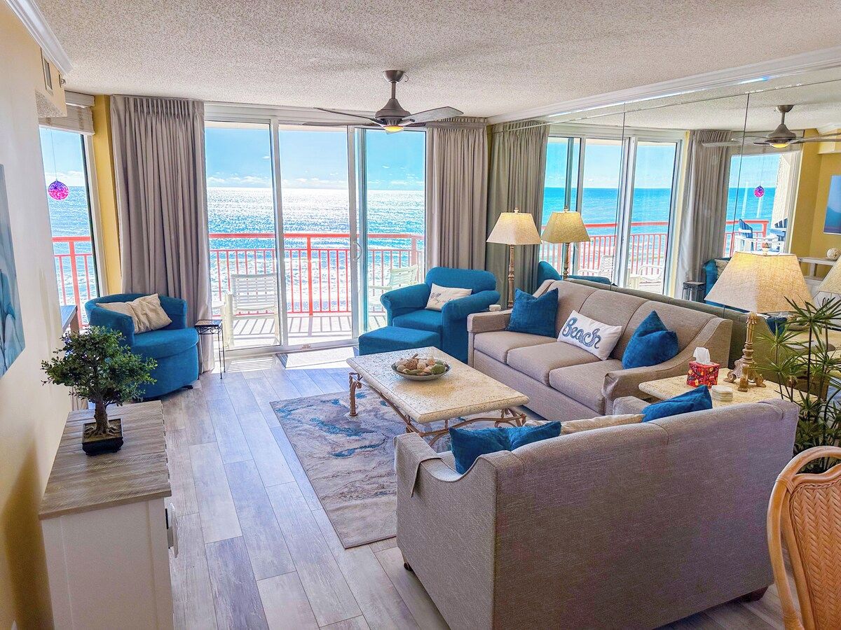 Un vaste salon avec vue sur la mer, aménagé avec des canapés et une table basse.