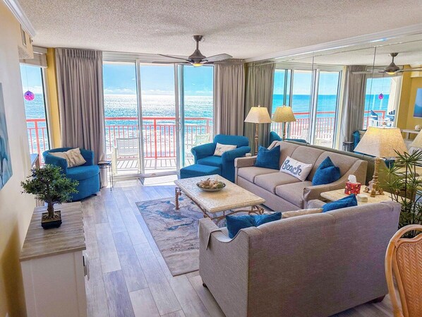 A spacious living room with a view of the sea, furnished with sofas and a coffee table.
