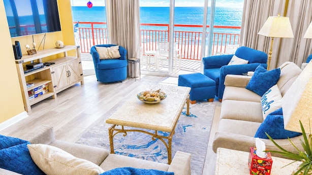 A living room with a TV, sofa, and a view of the sea.