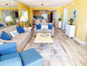 A living room with a sofa, a coffee table, and a dining area with chairs and a table.