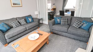 Ein Wohnzimmer mit zwei grauen Sofas, einem Holztisch und einem gerahmten Bild an der Wand.