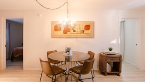 A dining area with a round table, six chairs, a chandelier, and a side table with books. - Charming 2 BR riverside stopover in Gold Hill. Private hot tub, river access, and just down the road from Del Rio Vineyards. Perfect base for exploring the Rogue Valley. Pet-friendly! (Gold Hill)