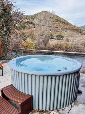A hot tub with a view of a river and hills in the background.