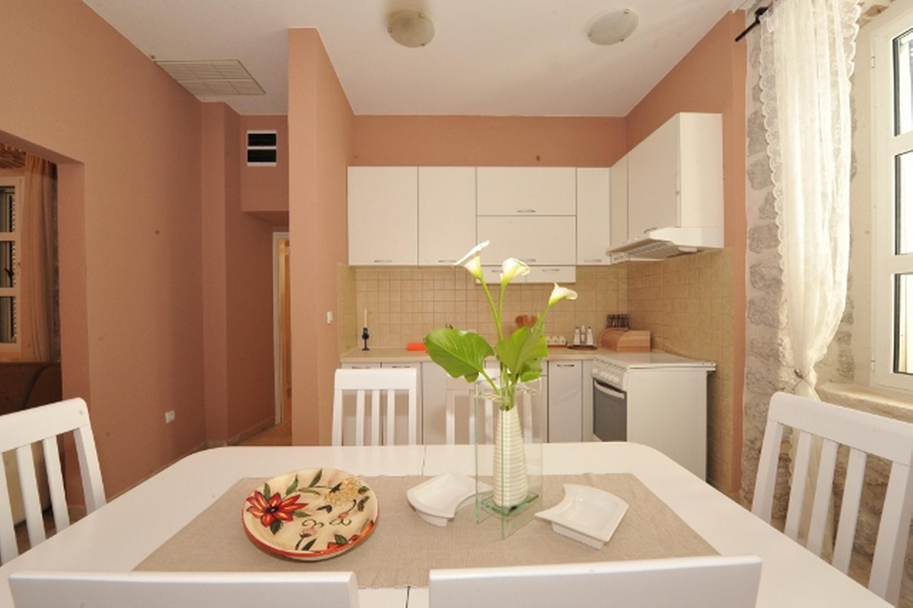 A dining area with a table set for two, a vase with flowers, and a plate with a floral design.