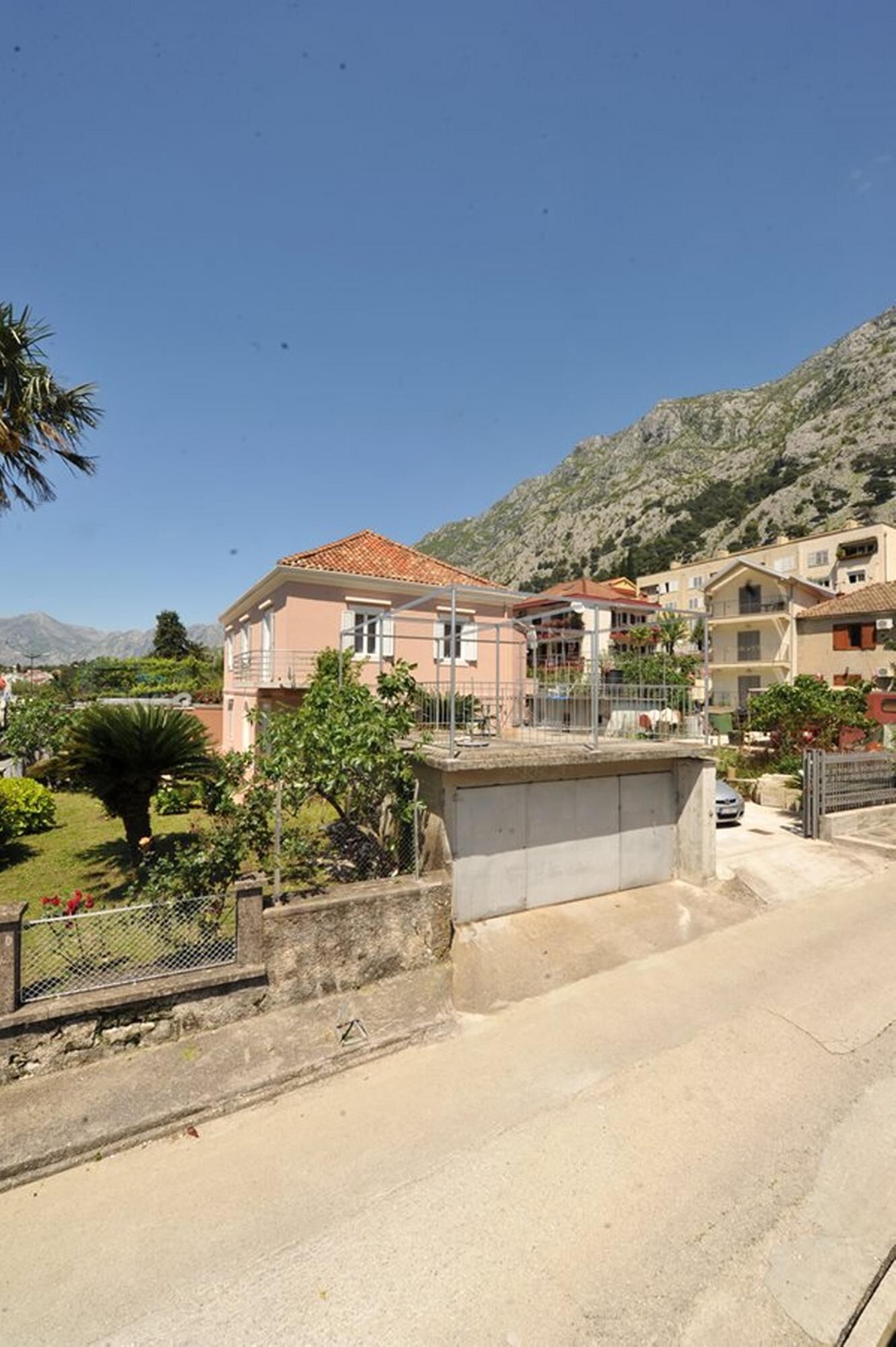 A residential area with houses, a paved road, and a mountainous backdrop.