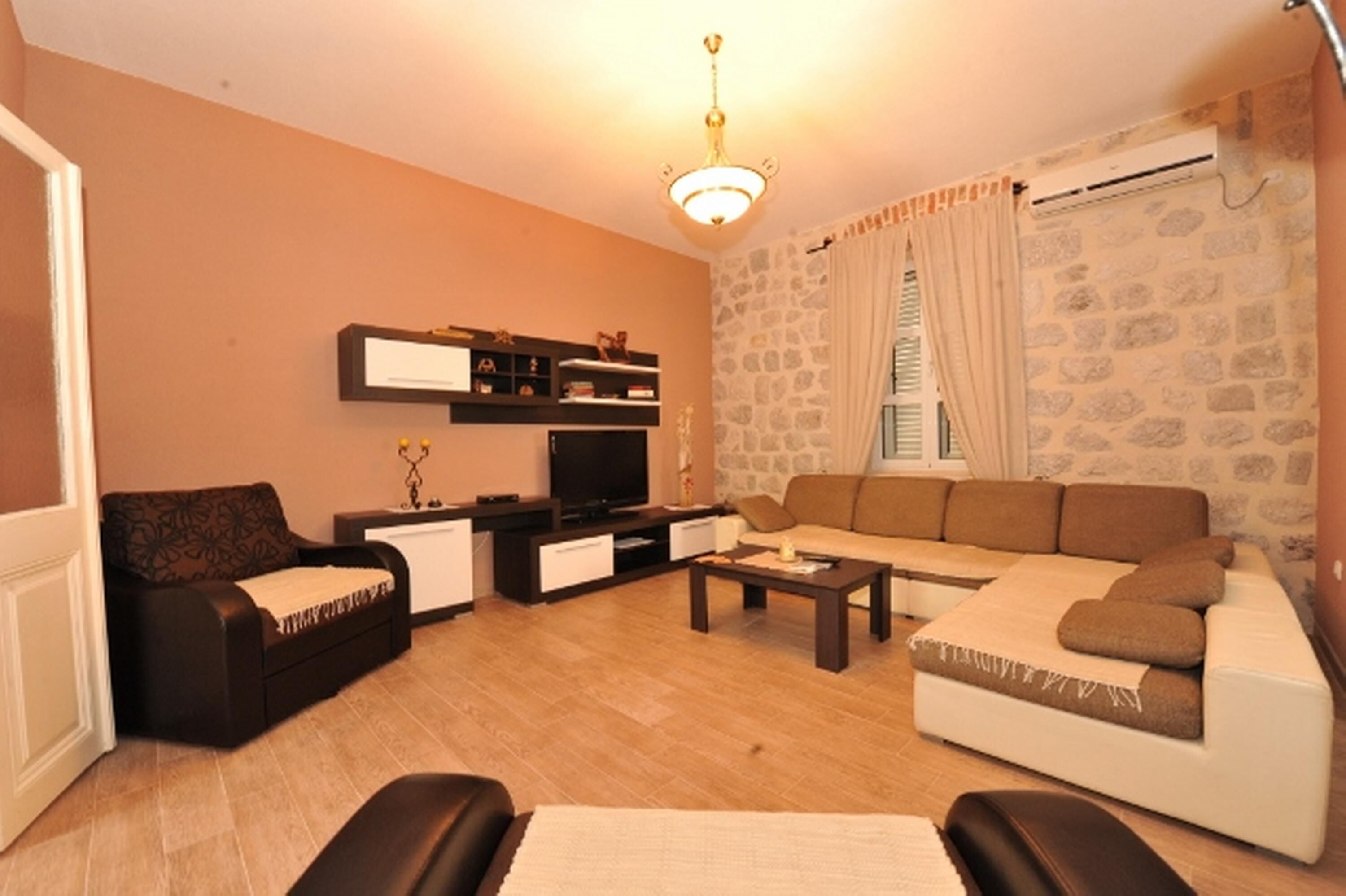 A living room with a sofa, a coffee table, a TV, and a stone wall.