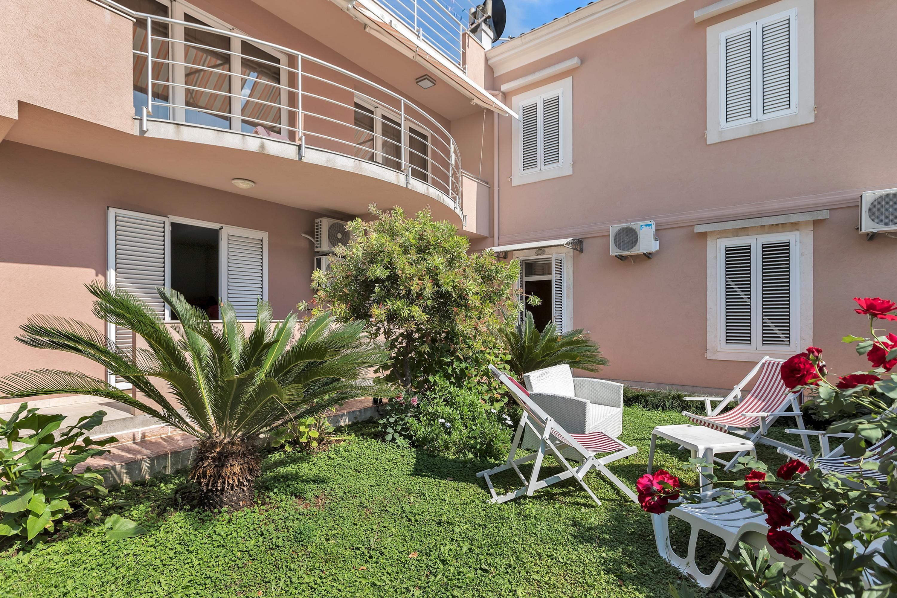 A courtyard with a palm tree, a small garden, and outdoor furniture.