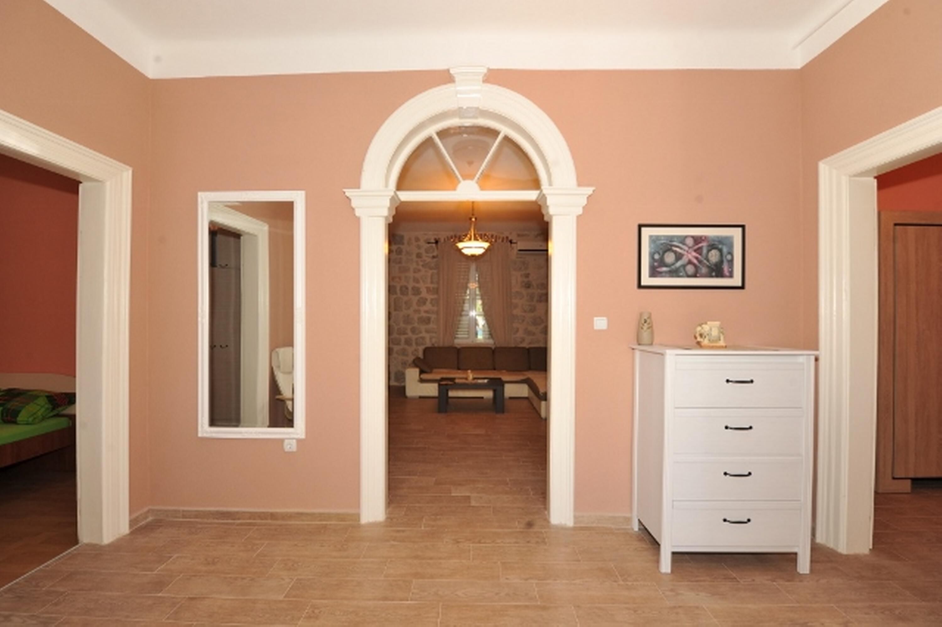 A hallway with a white dresser, a framed picture on the wall, and a stone wall in the background.