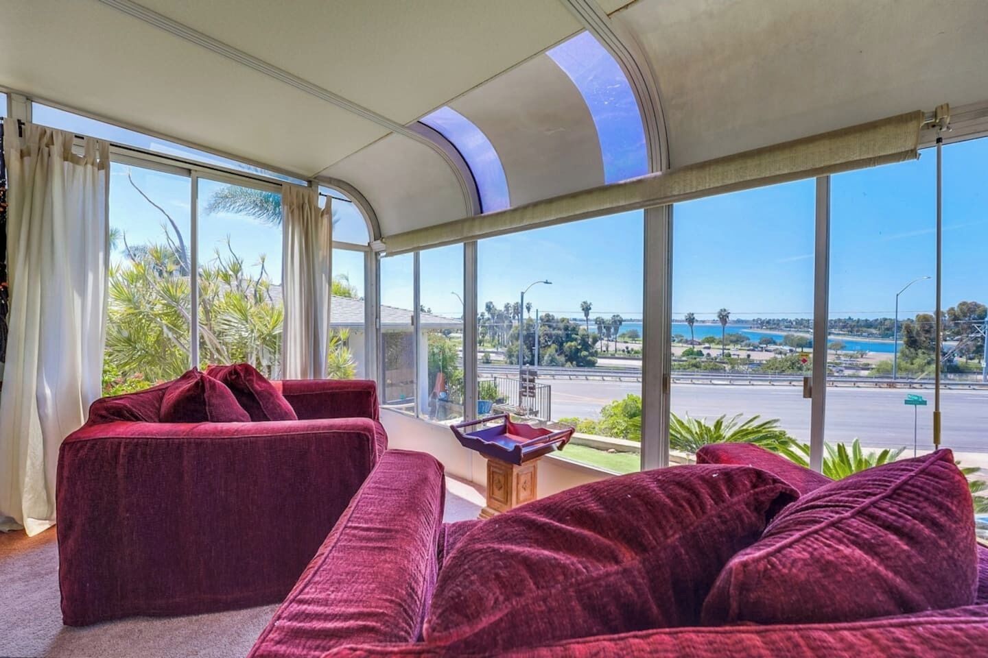 Un salón moderno con techo curvo y ventanas amplias que ofrecen vista a un paisaje urbano y al agua.