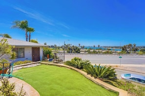 A residential property with a well-maintained lawn, a small shed, and a view of a coastal area with a road and a body of water. - View of Mission Bay plus A/C, pets, and parking (San Diego)