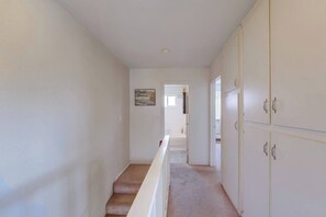 A hallway with carpeted stairs leading to a door, white walls, and a framed picture on the wall. - View of Mission Bay plus A/C, pets, and parking (San Diego)