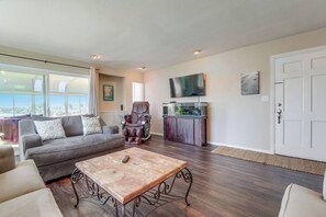 A living room with a sofa, a massage chair, a coffee table, a fish tank, and a television. - View of Mission Bay plus A/C, pets, and parking (San Diego)