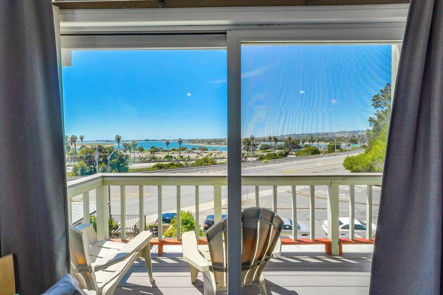 Un balcon donnant sur une zone côtière, avec vue sur une route et la végétation environnante.