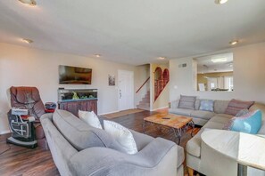 A spacious living room with a sofa set, a massage chair, a coffee table, and a staircase with a red railing. - View of Mission Bay plus A/C, pets, and parking (San Diego)