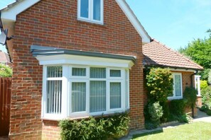 A red brick house with a bay window and a small garden.