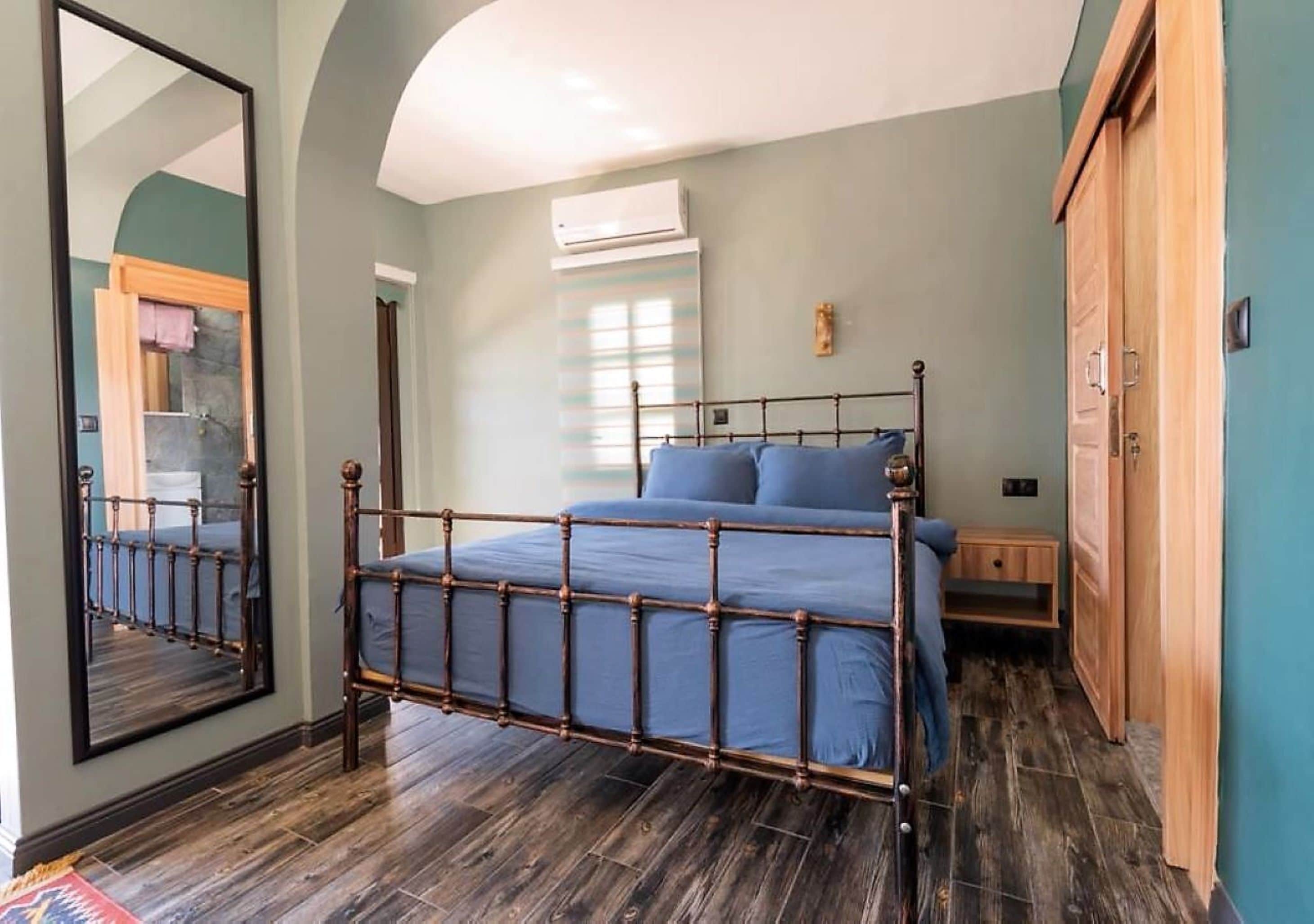 A bedroom with a wooden four-poster bed, a large mirror, and a wardrobe.