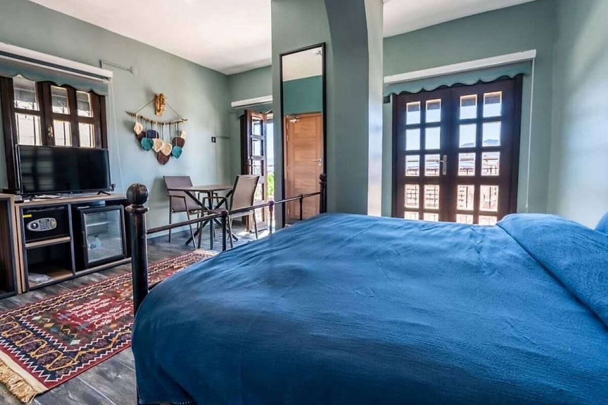 A bedroom with a large bed, a television, a desk, and a chair.
