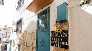 A building with a stone facade, a teal door, and a sign for 'LIMAN DELUX BOUTIQUE HOTEL CAFE'. - Liman Deluxe Hotel (Marmaris)
