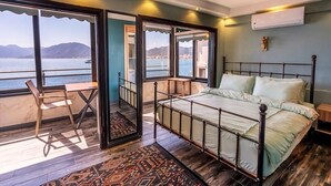 A bedroom with a large window, a bed, a chair, and a small table. - Liman Deluxe Hotel (Marmaris)