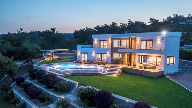 Una casa moderna de dos pisos con piscina, mobiliario exterior y un jardín bien cuidado.