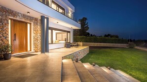 Una casa moderna de dos plantas con fachada de piedra, una puerta de madera grande y un patio exterior bien iluminado.