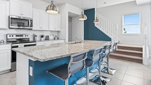 Eine moderne Küche mit weißen Schränken, einer Granit Arbeitsplatte, Edelstahlgeräten und einer blauen Akzentwand.