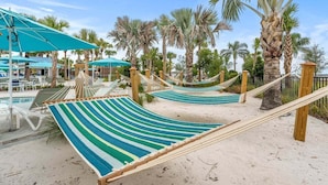 Ein Strandbereich mit Hängematten, Palmen und einem Pool.