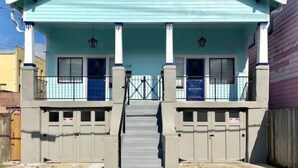 Une maison à deux étages, à la façade bleu clair, dotée d’un porche avec des colonnes et d’une entrée fermée par un portail.