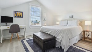 Une chambre à coucher avec un lit, un bureau, une chaise et une fenêtre avec des stores.