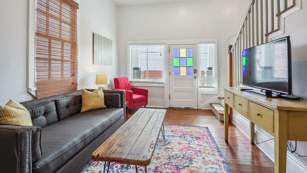 Un salon comprenant un canapé, un fauteuil rouge, une table basse en bois et un téléviseur posé sur un meuble en bois.