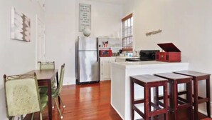 Une cuisine avec un îlot central, un réfrigérateur et un four à micro-ondes. On y trouve des chaises et une table à manger.