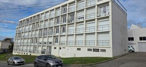 Ein mehrstöckiges Gebäude mit Balkonen und einem Parkplatz, mit der Beschilderung "Residence Les Merveilles Blanches".