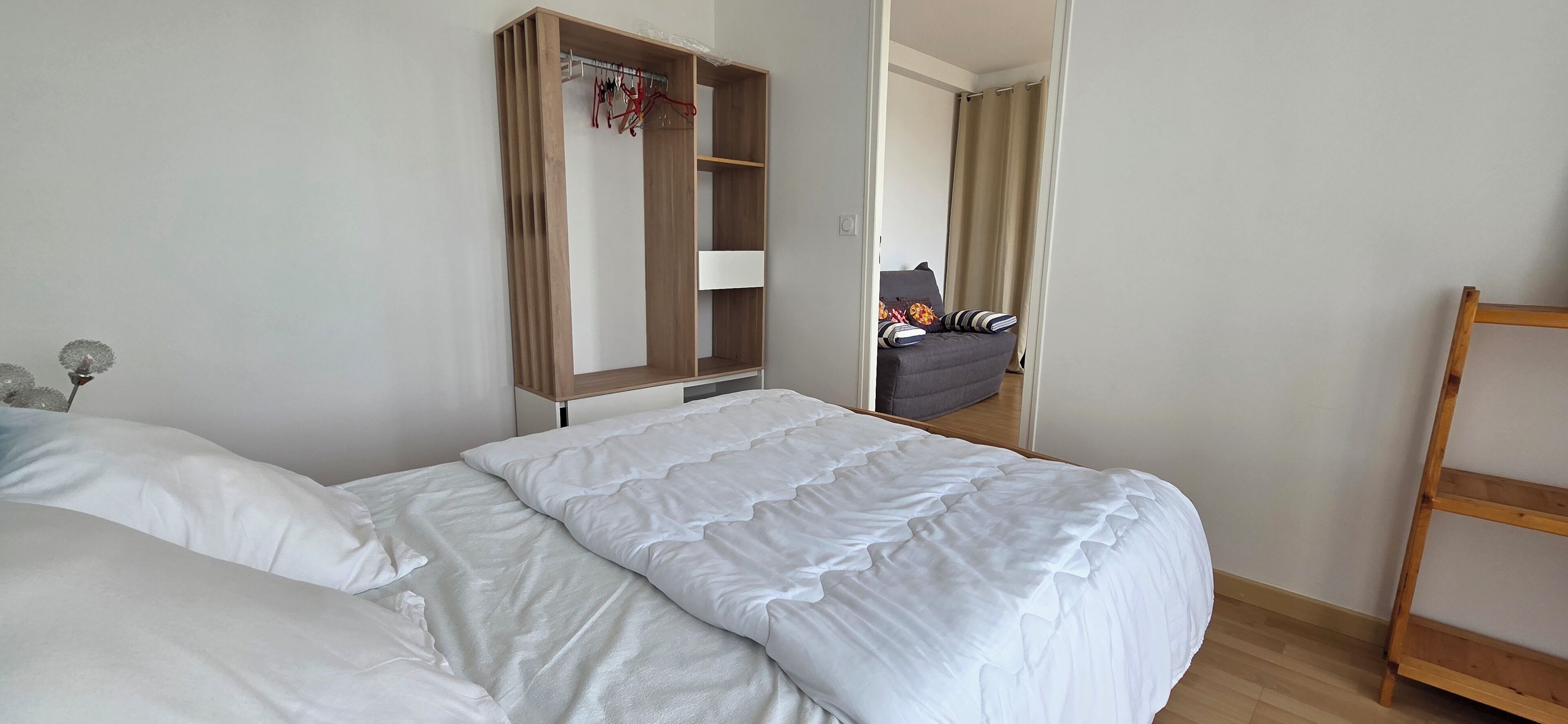 Ein Hotelzimmer mit einem Bett, einem Holzschrank, einem Stuhl und einer Holzleiter.