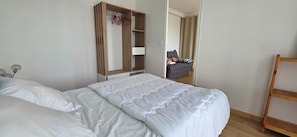Een hotelkamer met een bed, een houten garderobe, een stoel en een houten trap.