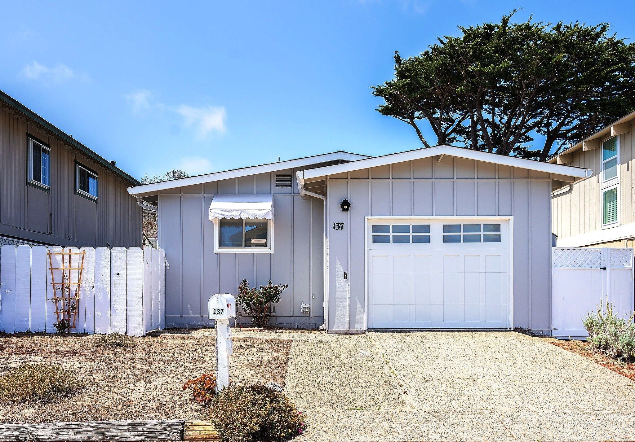 A single-story house with a garage, a mailbox, and a number sign.