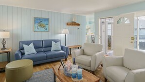 Una sala de estar con un sofá azul, un sillón color beige, una mesa de centro de madera y una lámpara.