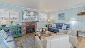 Una sala de estar con chimenea, paredes azules, un sofá azul y una mesa de centro de madera.
