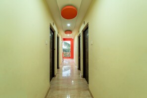 A hallway with a marble floor, doors on both sides, and a red accent wall at the end. - Itsy Hotels Adams Beach Resort, 350 Mtrs From Baga Beach (Baga)