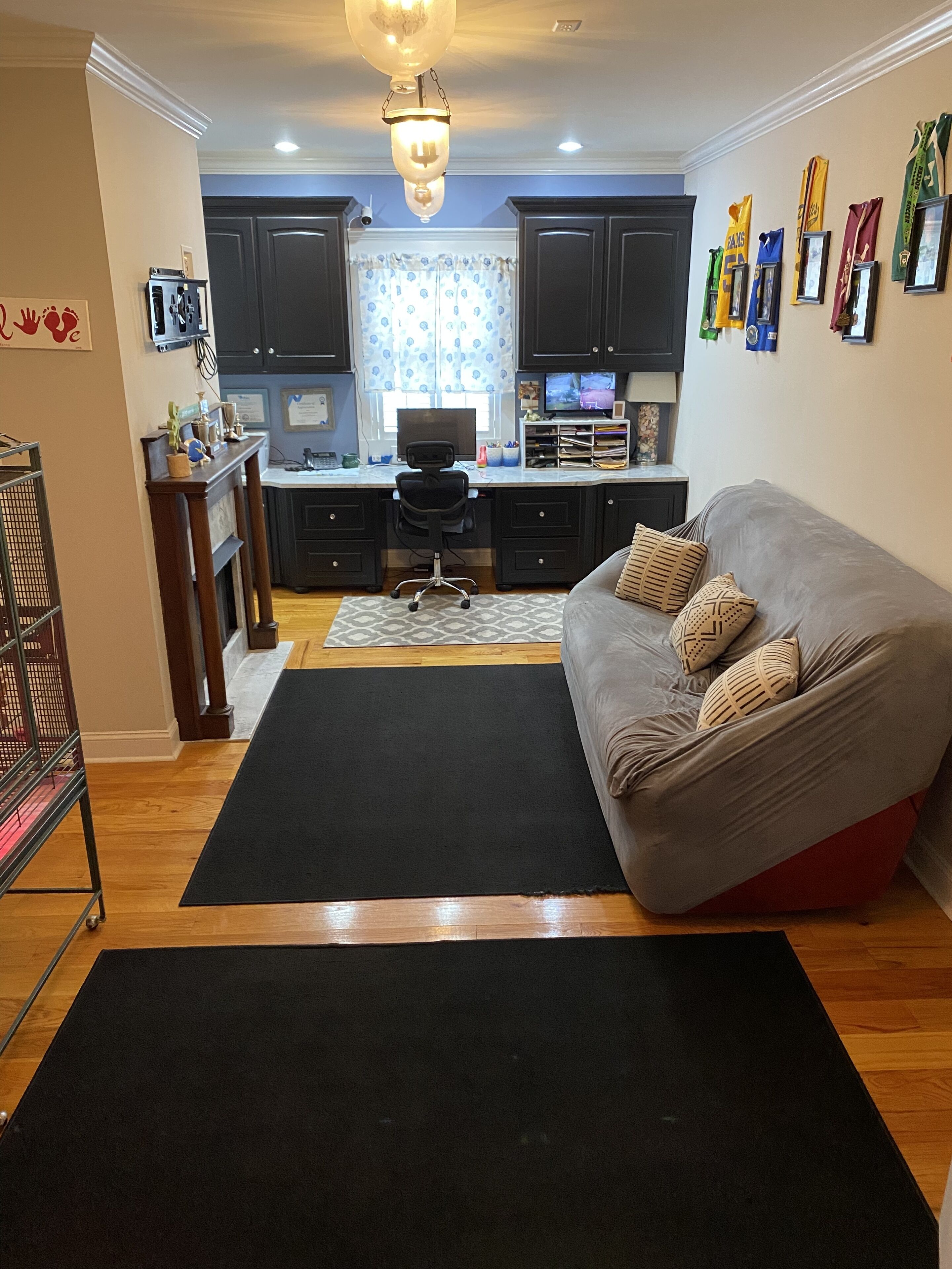 A modern living room with a grey sofa, black rug, and a kitchen area with dark cabinets and a dining table.