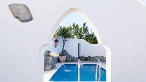 A swimming pool with a stone wall, a hanging planter, and a small waterfall feature. - Casa Lola - House N1 in Zahora (Zahora)