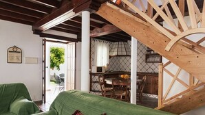 A cozy living area with a green sofa, a wooden staircase, and a dining area with a table and chairs. - Casa Lola - House N1 in Zahora (Zahora)