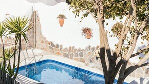 A pool area with a stone wall, potted plants, and a tree. - Casa Lola - Casa N2 en Zahora (Zahora)