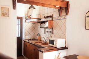 A kitchen with a wooden countertop, a microwave, and a tiled backsplash.