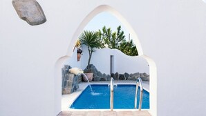 Una piscina con un muro de piedra y una maceta colgante.