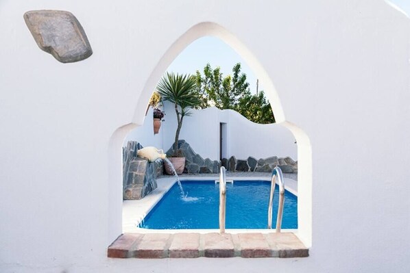 A pool with a stone wall and a hanging planter.