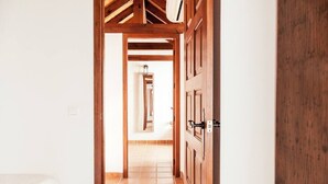 Un pasillo con puertas de madera y suelo de baldosas que lleva a otra habitación.