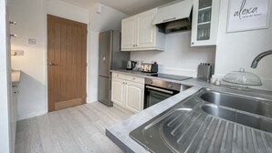 Een moderne keuken met witte kasten, een roestvrijstalen spoelbak, een broodrooster en een koffiezetapparaat.