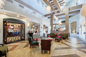 Relax in the spacious lobby with comfortable seating, a mounted TV, and decorative artwork.